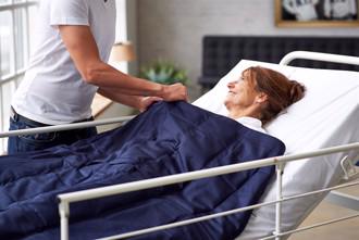 En ældre kvinde i en seng, ligger med spektrumshops sansedyne
